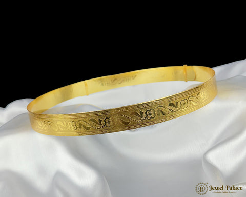Gold bracelet with intricate designs on a white fabric background