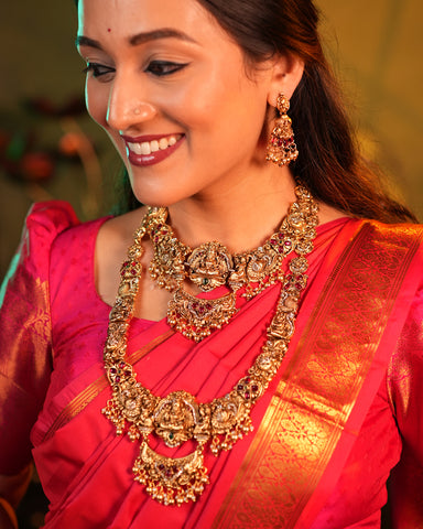 Woman wearing traditional gold jewelry and a red saree with a blurred background