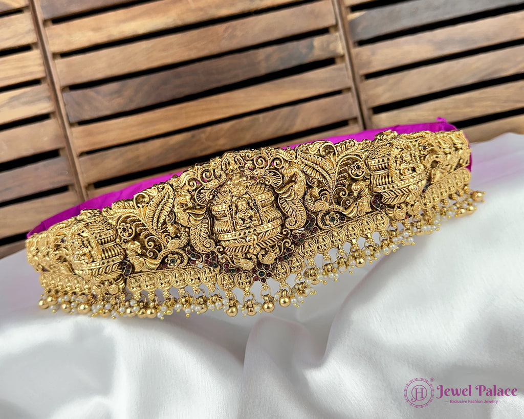 Gold decorative belt with intricate patterns on a white fabric background