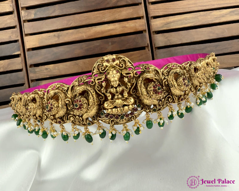 Gold and green decorative headband on a white surface with a wooden background