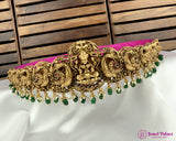 Gold and green decorative headband on a white surface with a wooden background