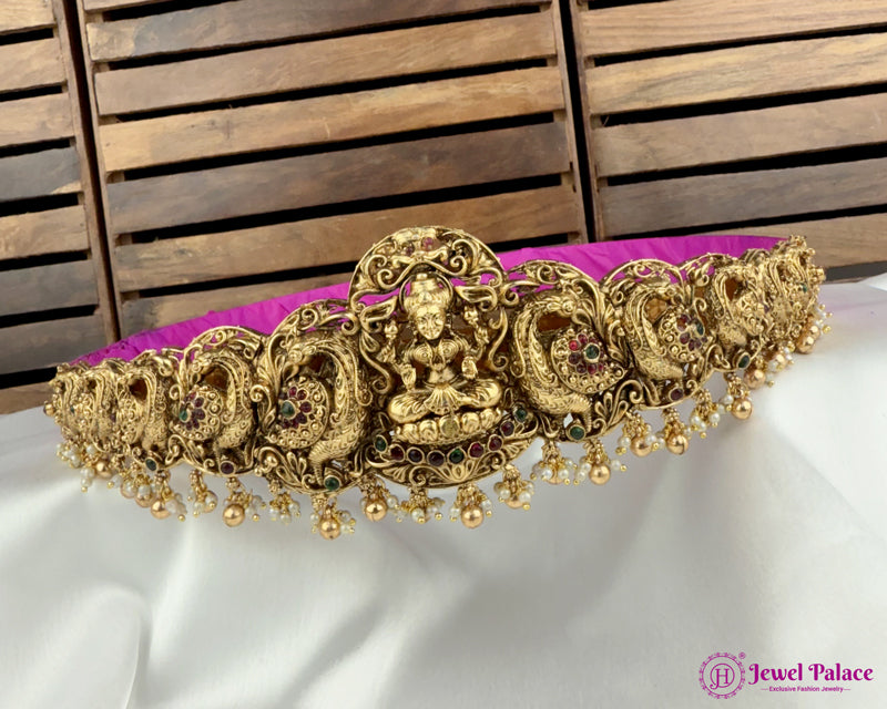 Decorative gold necklace on a white and purple fabric with a wooden background