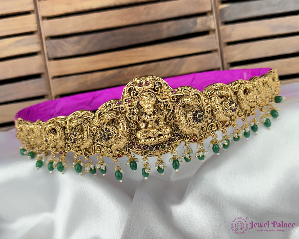 Gold necklace with green beads on a white surface with a wooden background