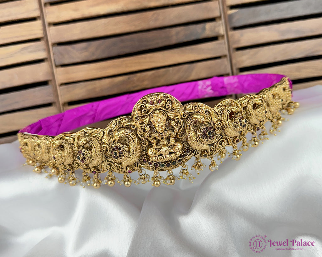 Gold necklace with intricate designs on a white fabric background