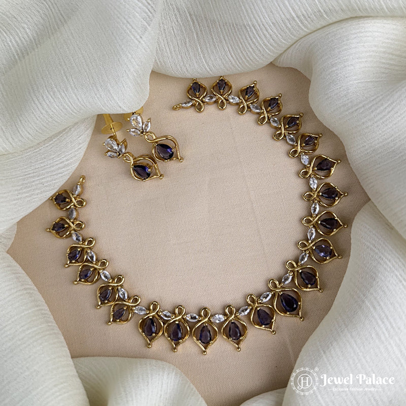Gold necklace with purple stones on a white fabric background, brand 'Jewel Palace' visible.