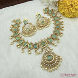 Ornate gold and green jewelry set on a white fabric background with yellow flowers.