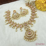 Ornate gold and pink jewelry set on a white fabric background with yellow flowers.