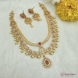 Gold necklace with pink stones and matching earrings on a white fabric background with yellow flowers.