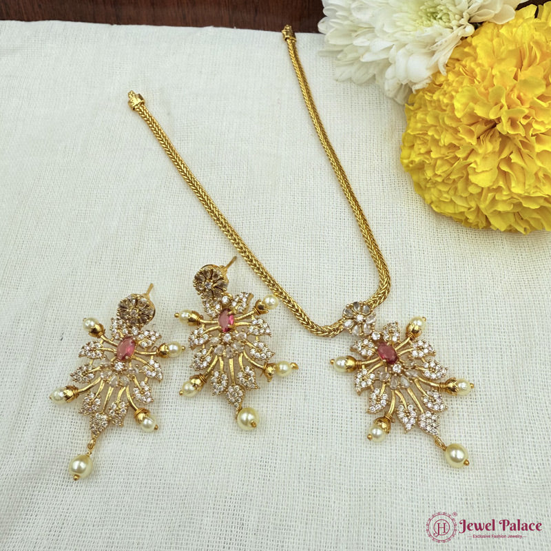 Gold necklace and earrings set on a white fabric background with yellow flowers.