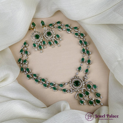 Emerald necklace and earrings on a white fabric background with 'Jewel Palace' branding.