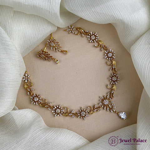 Gold necklace with floral design on a mannequin bust, surrounded by white fabric.