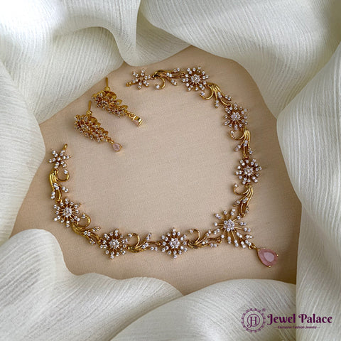 Gold necklace with pink stones on a white fabric background, featuring the brand 'Jewel Palace'.