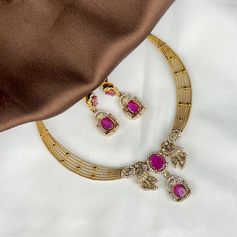 Gold necklace with pink gemstones on a white background