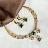 Gold necklace with green gemstones on a white background