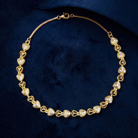 A gold heart-link chain necklace adorned with clear pavé stones, displayed on a textured dark blue velvet background.