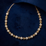 A gold heart-link necklace with clear pavé stones, displayed on a textured dark navy blue fabric background.