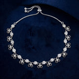 A silver-toned floral necklace with clear rhinestone-encrusted flower charms, displayed on a dark navy velvet background.