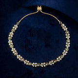A gold-toned necklace with multiple rows of clear gemstones arranged in floral clusters, displayed on a dark navy velvet background.