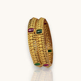 Gold bracelet with embedded gemstones on a white background