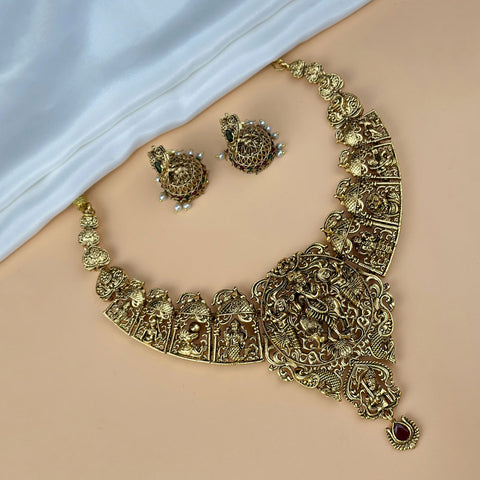 Gold necklace and earrings set on a beige surface