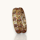 Gold bangles with gemstone inlays on a white background