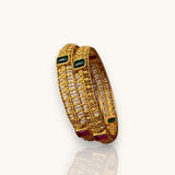 Gold bangles with gemstones on a white background