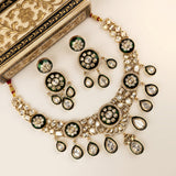 Gold-plated Kalka-style necklace and matching earrings with green enamel floral motifs and clear stone embellishments, displayed on a cream background next to an ornate decorative box.