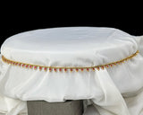 Gold anklet with red stones on a white fabric background
