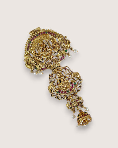 Gold earrings with intricate designs and gemstones on a light beige background