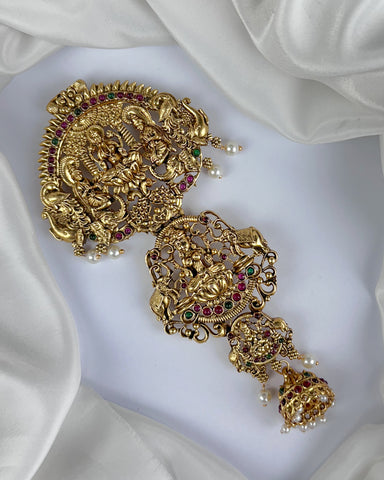 Gold earrings with intricate designs and gemstones on a white fabric background