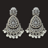 A pair of ornate silver-toned chandelier earrings decorated with clear stones and white pearl-like drops, shown on a solid black background.