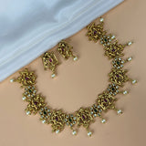 Gold necklace and earrings set on a beige surface