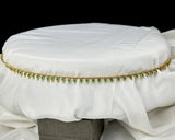 White cushion with gold and green decorative band on a black background