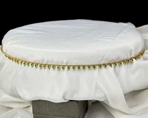 White cushion with gold and green decorative band on a black background
