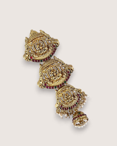 Ornate gold earrings with red gemstones on a light gray background