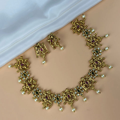 Gold necklace and earrings set on a beige surface