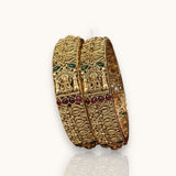 Gold bracelet with green and red stones on a white background