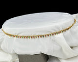 Decorative belt with gemstones on a white fabric background