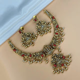 Ornate gold necklace with red stones and earrings on a mannequin.