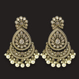 A pair of ornate Indian jhumka earrings with antique gold-plated metalwork, set with clear stones and decorated with dangling white faux pearls, shown against a solid black background.
