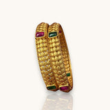 Gold bangles with gemstones on a white background