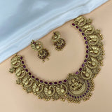 Ornate gold necklace with red stones and matching earrings on a person's neck.