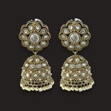A pair of ornate Indian jhumka earrings with gold-plated filigree, clear stone embellishments, and small white pearl bead drops, shown against a solid black background.