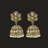 A pair of ornate gold-toned Indian jhumka earrings with white stone embellishments, displayed against a solid black background.