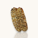 Gold bracelet with intricate designs and gemstones on a white background