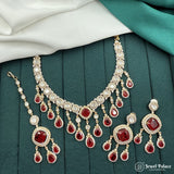 Ornate necklace with red gemstones on a green fabric background
