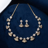 Gold-tone necklace and matching drop earrings with fan-shaped and floral motifs, displayed on a dark blue velvet jewelry box.