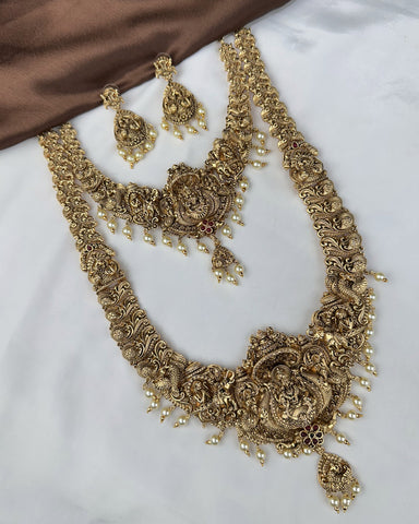 Gold necklace and earrings set on a white surface