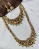 Gold necklace with green and red stones on a white surface