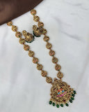 Decorative gold necklace with green and red stones on a white background